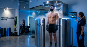 A professional, editorial-style photograph of a focused athlete undergoing cryotherapy treatment in
